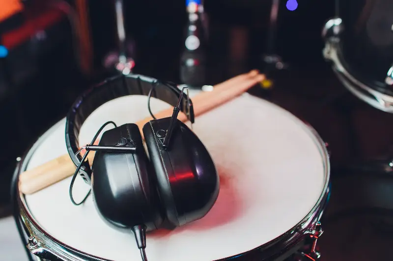 Casque audio et paire de baguettes posés sur la peau d’une caisse claire