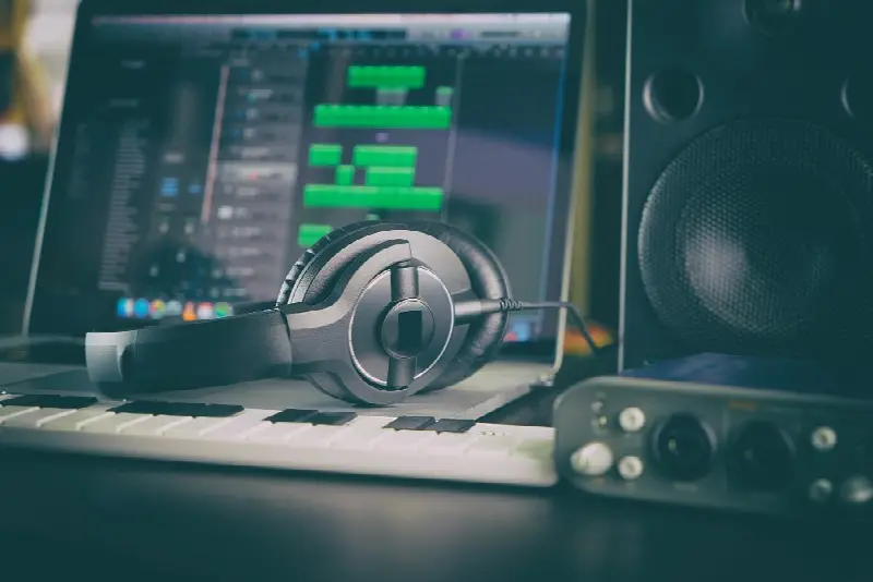 Casque audio sur un clavier maître devant un ordinateur ouvert sur un logiciel de musique