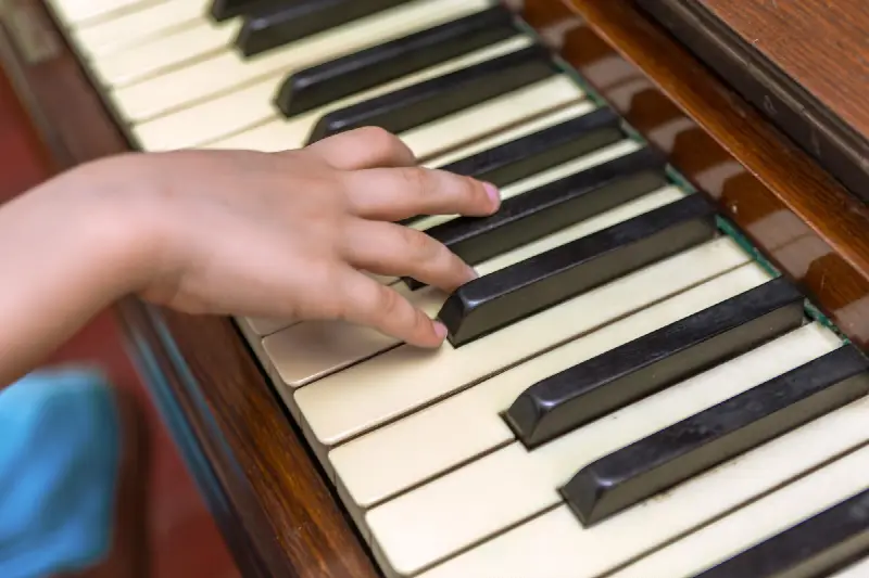 Main d'un enfant sur le clavier d'un vieux piano en bois