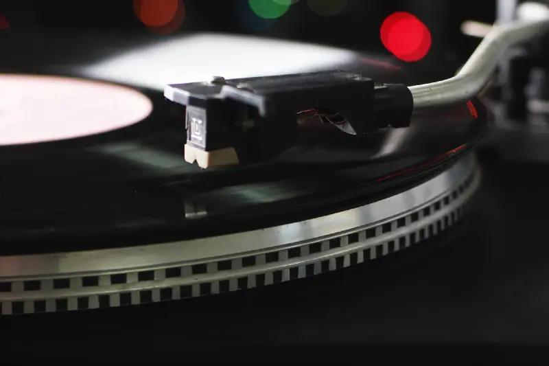 Cellule et bras de lecture au-dessus d'un disque, sur un plateau bordé de points stroboscopiques