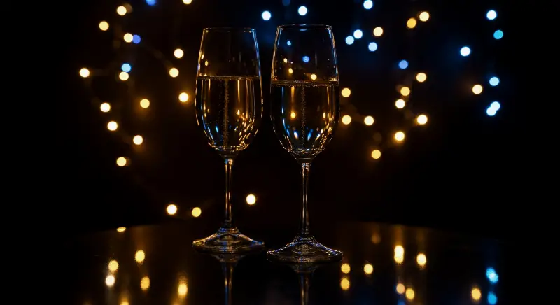 Deux flûtes de champagne sur une table sombre et brillante, guirlande lumineuse floue en arrière-plan