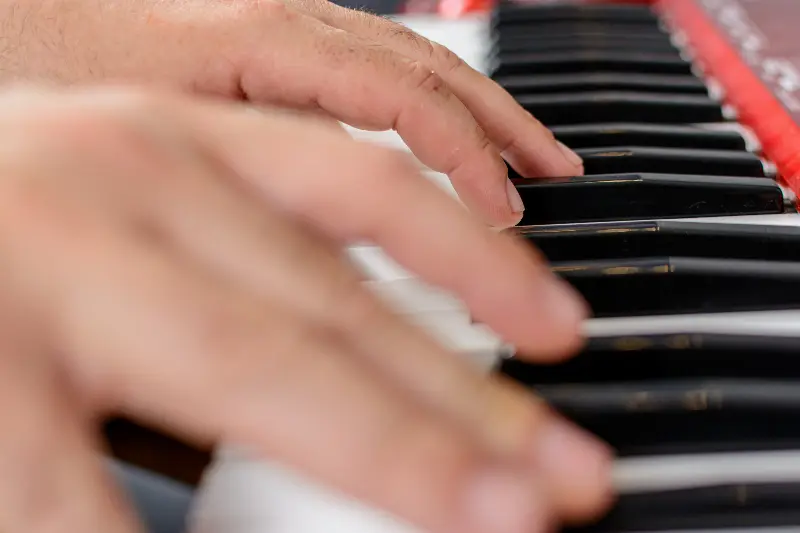 Deux mains qui jouent sur un clavier de scène rouge