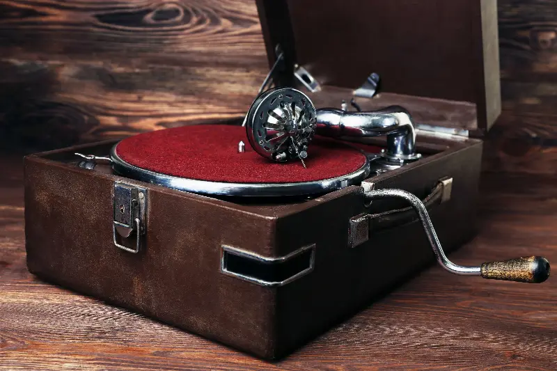 Gramophone portable ancien à manivelle, dans sa valise ouverte sur une table en bois