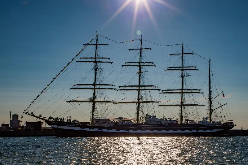 Grand voilier à quatre mâts, voiles serrées, à quai sous un soleil éclatant