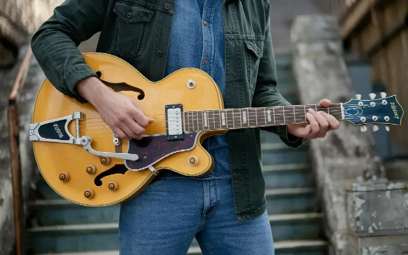 Mains d'un guitariste jouant sur une guitare électrique demi-caisse