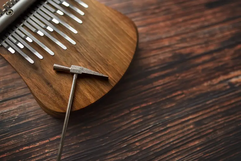 Kalimba en bois et son marteau d'accordage posés sur une table