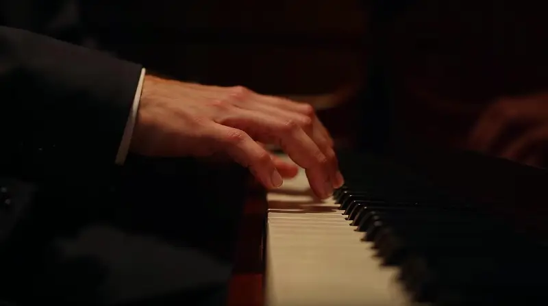 Mains d'un pianiste sur le clavier, dans la lumière tamisée d'un club