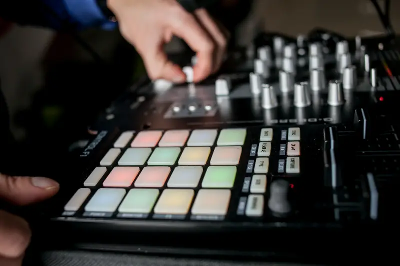 Mains sur un contrôleur de musique électronique : pads lumineux de couleur et rangées de potentiomètres