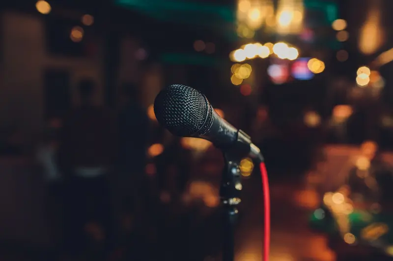 Micro sur pied au premier plan, lumières d’un bar floues en arrière-plan