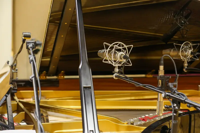 Micros de studio installés au-dessus d'un piano à queue ouvert, prêts pour un enregistrement