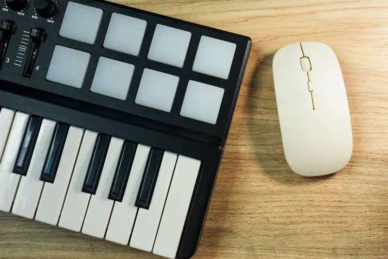 Petit clavier maître MIDI avec huit pads, posé sur un bureau en bois à côté d'une souris