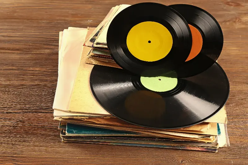 Pile de vieux disques vinyles et de pochettes usées sur une table en bois
