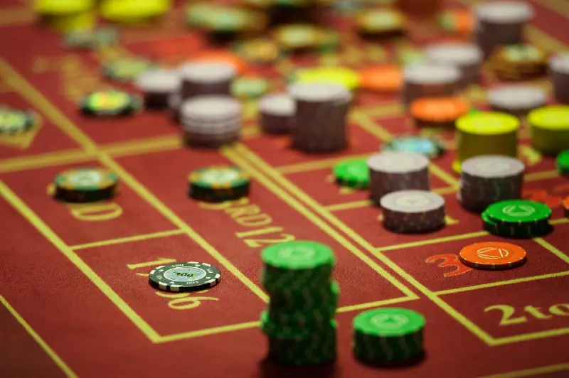 Tapis de roulette rouge couvert de piles de jetons de casino colorés