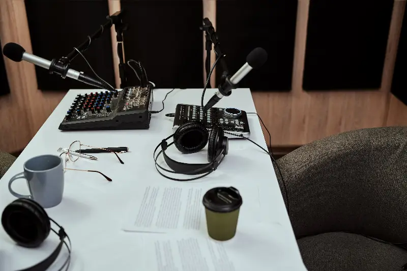 Table de studio de radio avec deux micros, une console de mixage, des casques et des feuilles de conducteur
