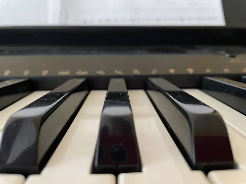 Touches d’un piano en gros plan, partition floue à l’arrière-plan